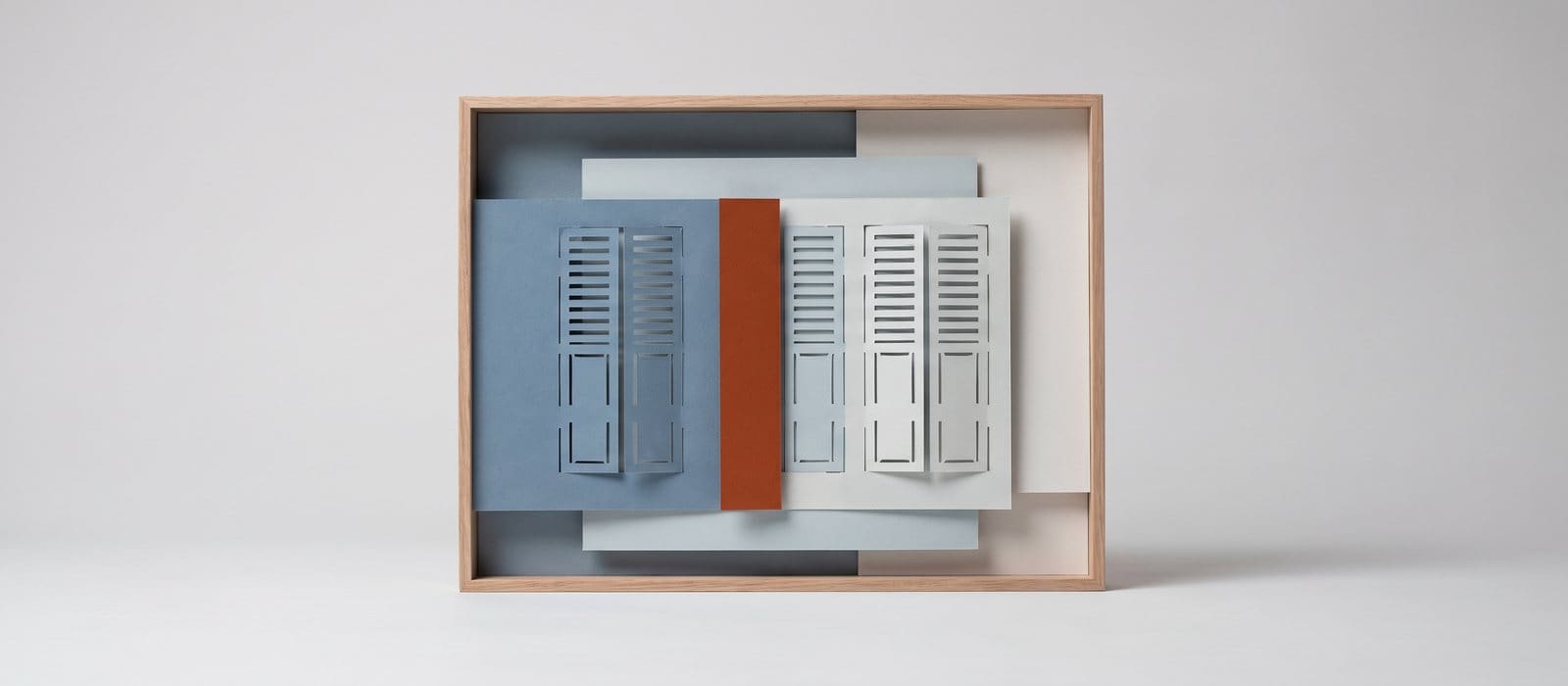 Cut-paper diorama of closed paper shutters in dusty blue with one orange layer