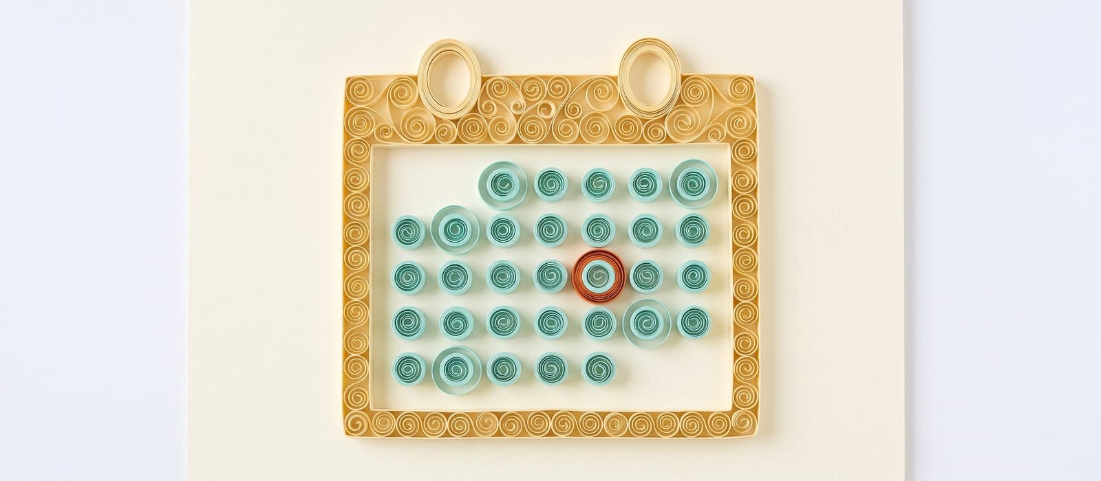 Paper quilling of a wall calendar made of teal paper coils, with several days circled and one circled in orange