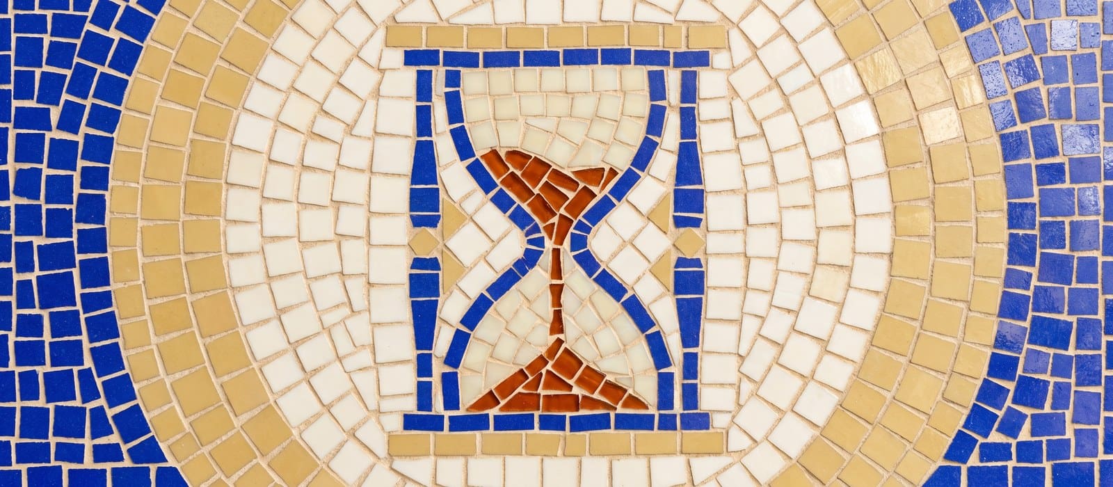 Mosaic tile artwork of an hourglass with burnt-orange sand running through it