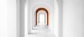 A long bright corridor of white arches, one arch in burnt orange, leading to an open doorway of daylight