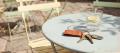 Instant-film photo of car keys on a burnt-orange leather fob beside a glass of water on a pale blue café table in sunshine