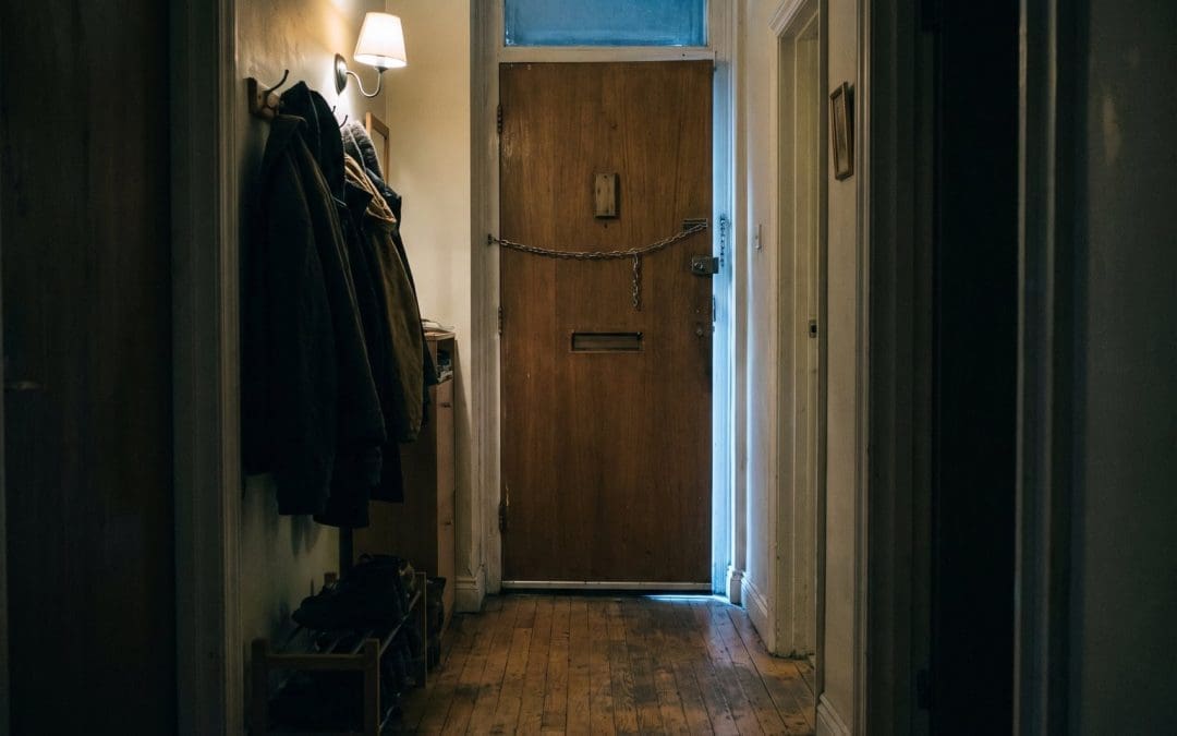 Apartment entrance hall at night with the front door closed and a security chain across it