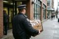 Police officer carrying a banker box of seized financial documents out of an office building